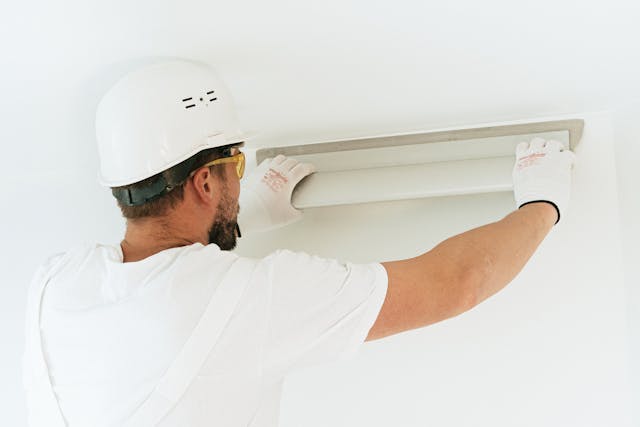 man in hard hat using a level on a wall